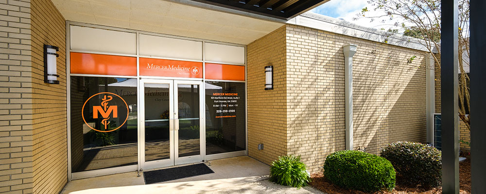 A sepia brick building with a Mercer Medicine Clay County sign above the door